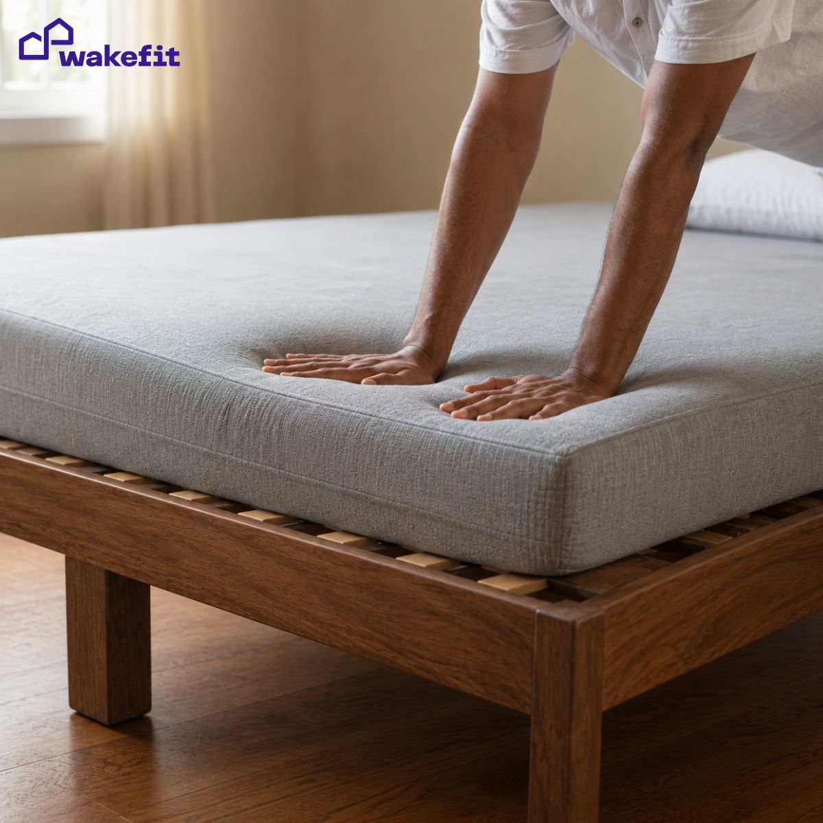 Hands pressing on a sagging mattress showing a visible depression caused by foam compression