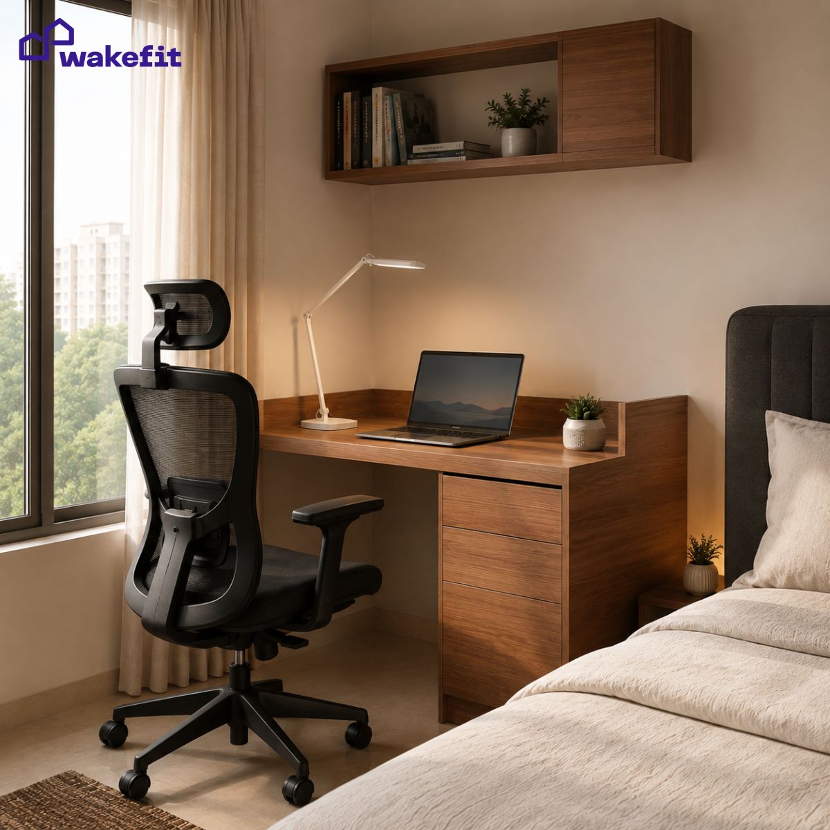 Wakefit study table, ergonomic office chair, and study lamp set up as a small room workspace with Wakefit storage bed in the background
