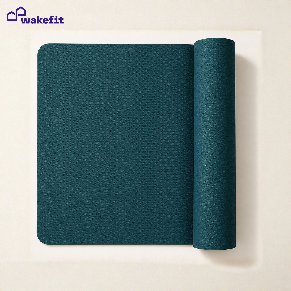 Deep teal yoga mat mid-unroll on white surface showing embossed grip texture - top-down product shot for yoga mat buying guide